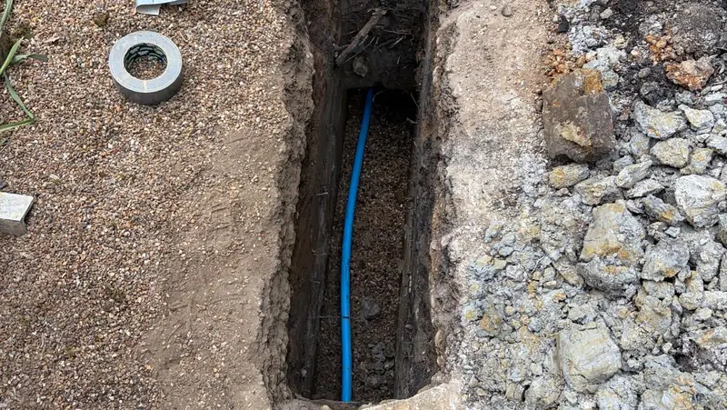 Open trench on an East Grinstead job showing the new blue MDPE water main pipe installed along the run
