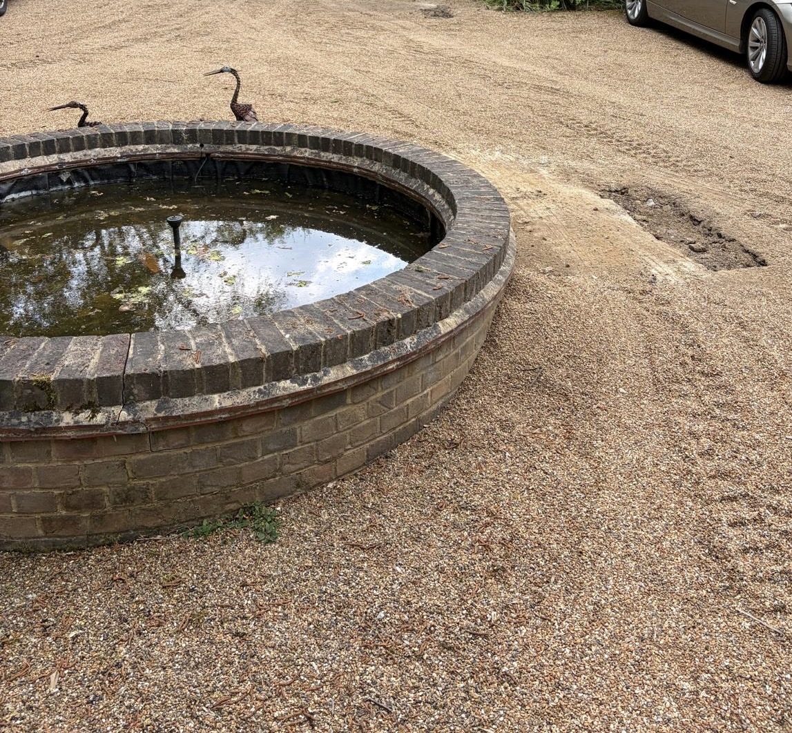 Trenchless water main replacement in Sussex — gravel driveway with ornamental pond left completely undisturbed