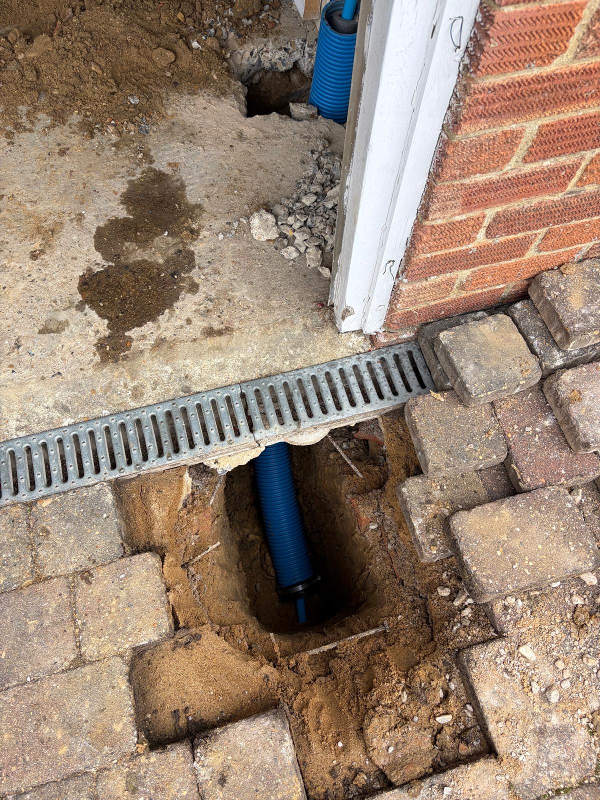 Water supply pipe entry into a residential property, protected in blue ducting.