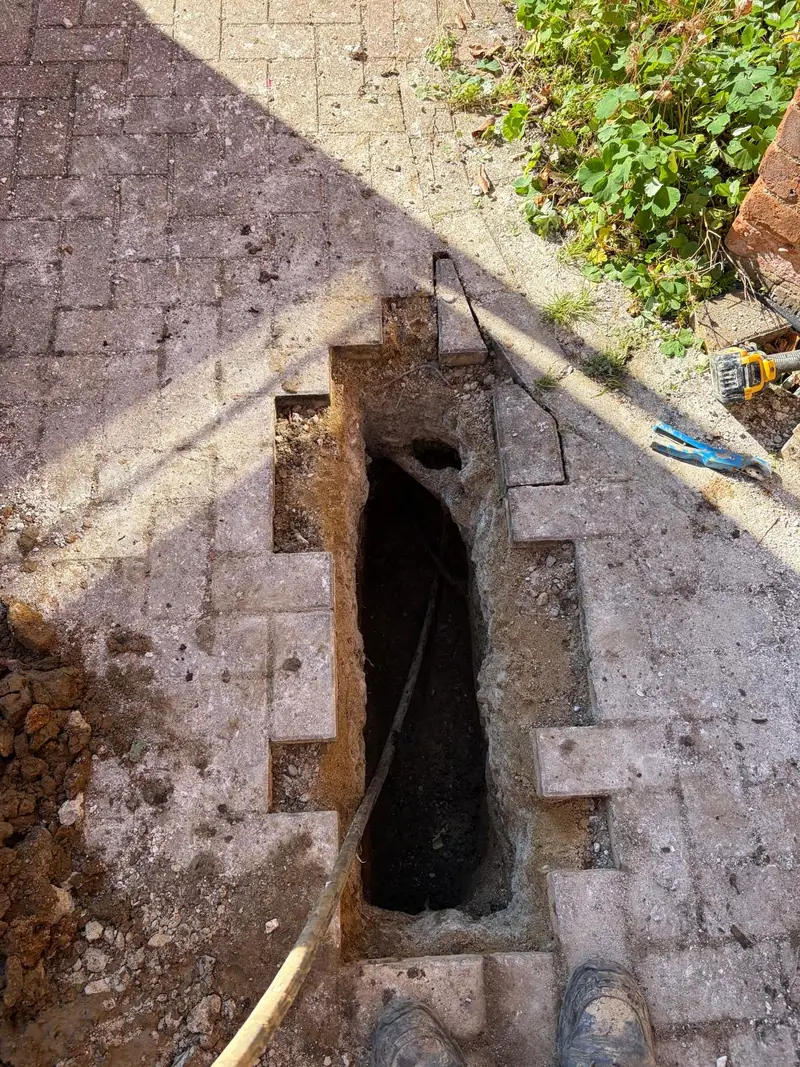 Access excavation through block paving during a water supply pipe installation.