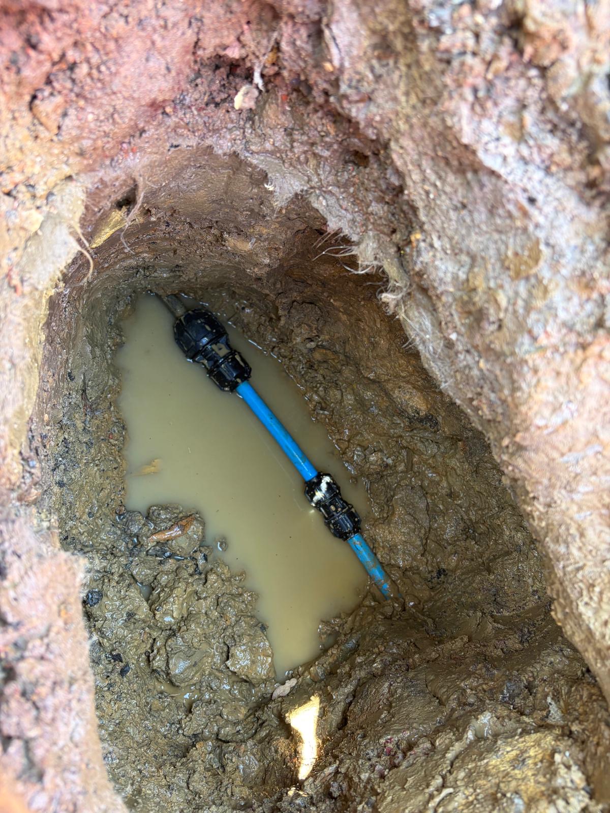 New 32mm blue MDPE water pipe joined with two WRAS-approved compression fittings in a wet excavation.