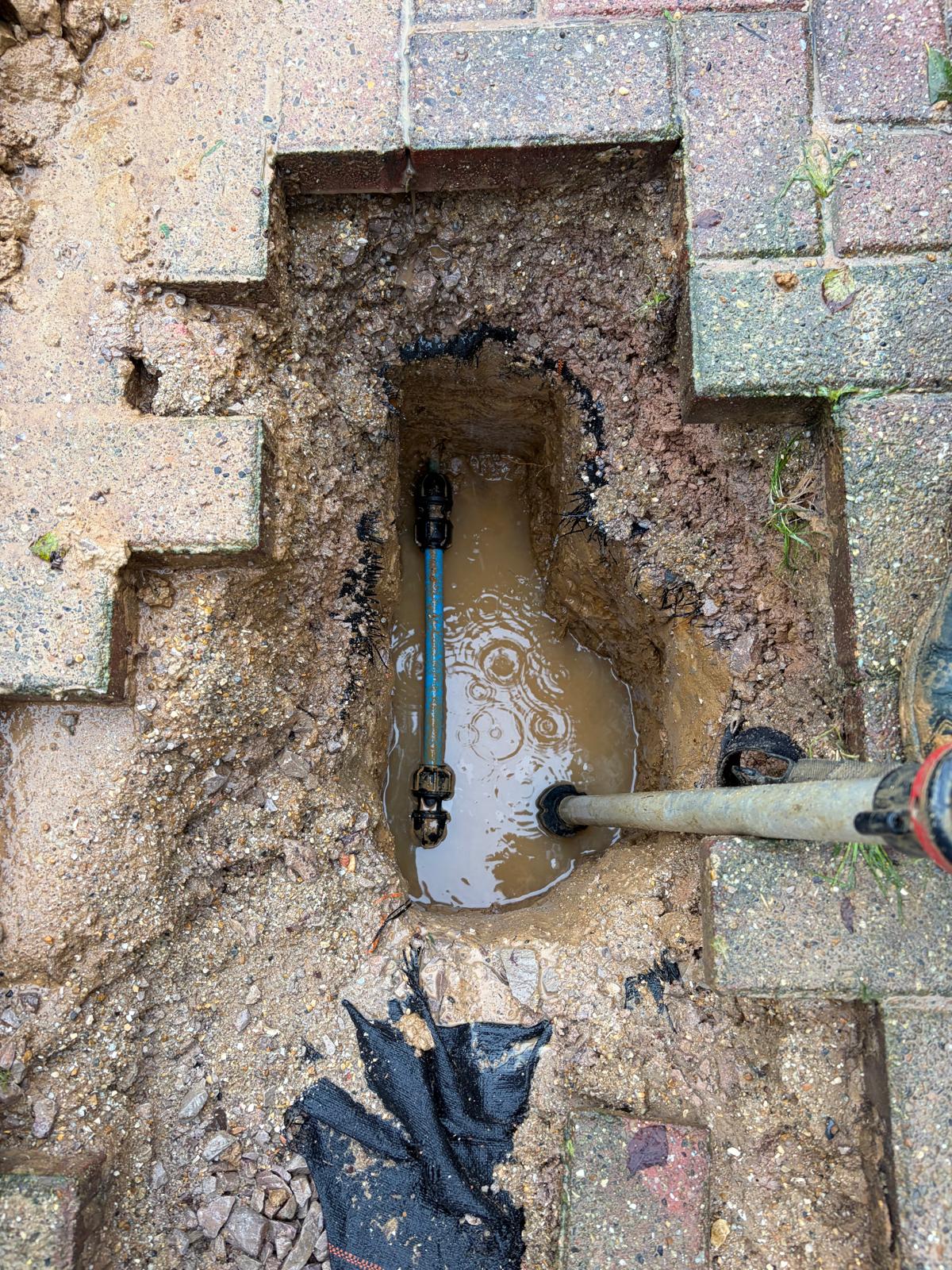 Repaired water supply pipe beneath block paving in Hassocks, with new mechanical fittings.